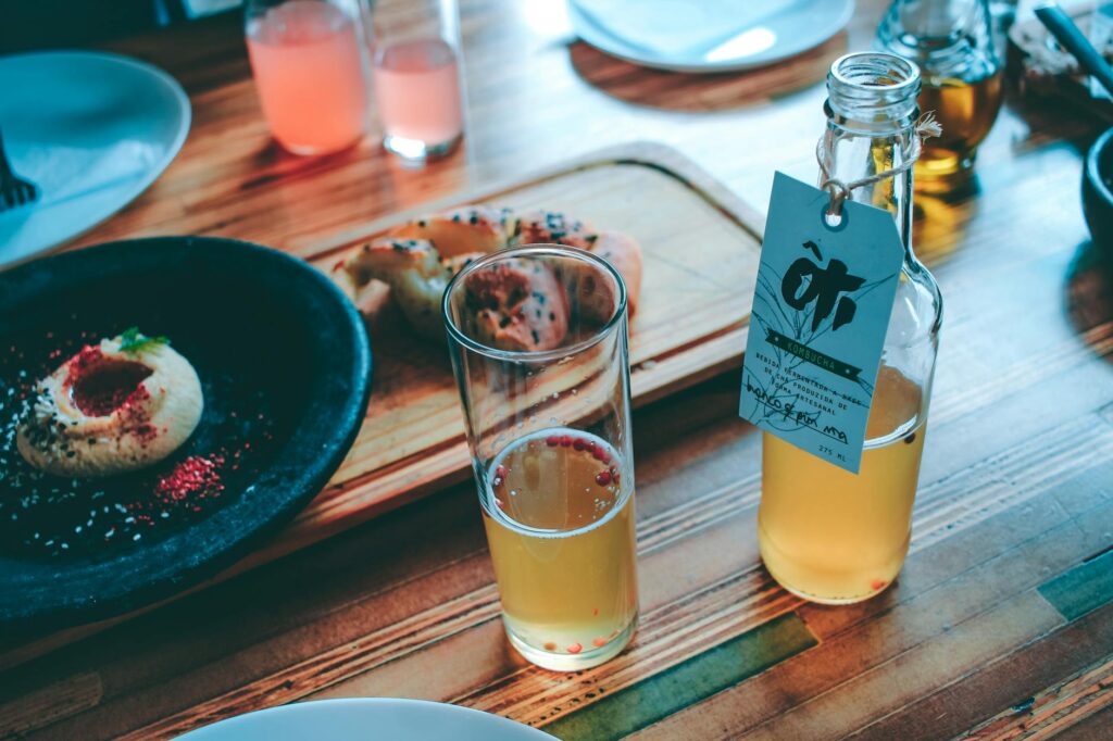 Chic indoor dining setup with a glass of kombucha and gourmet appetizer on a wooden table.