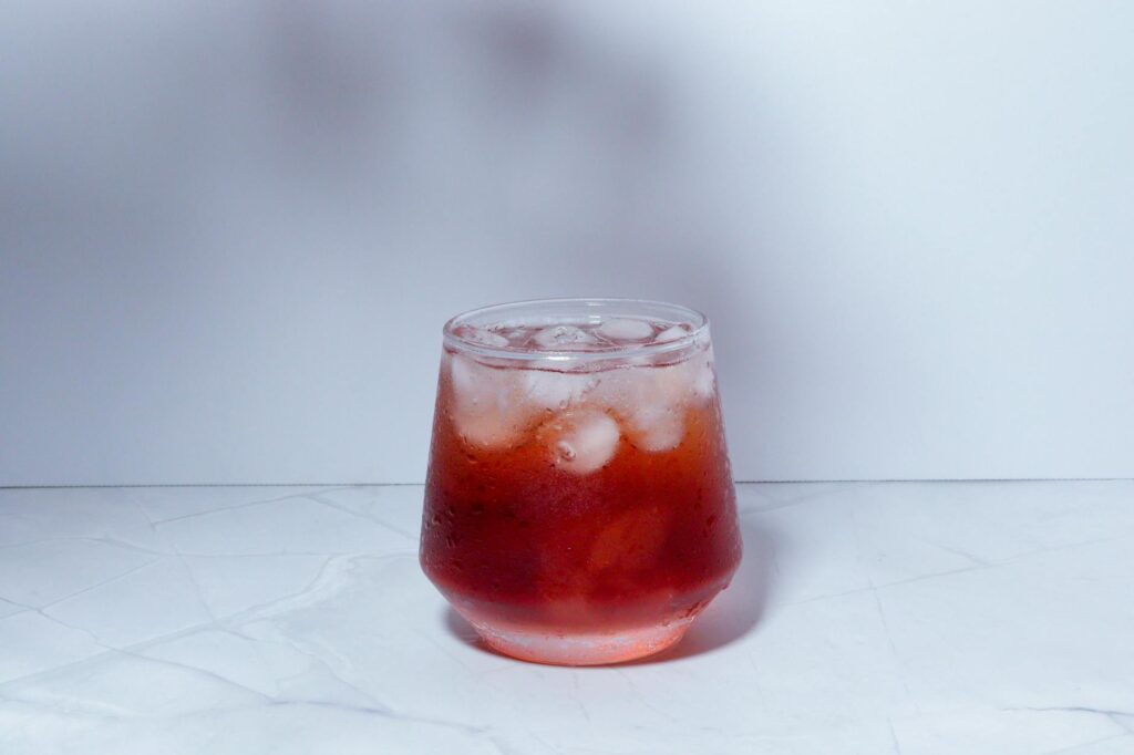 Elegant kombucha mocktail in a cocktail glass garnished with fresh herbs and citrus on a bar counter