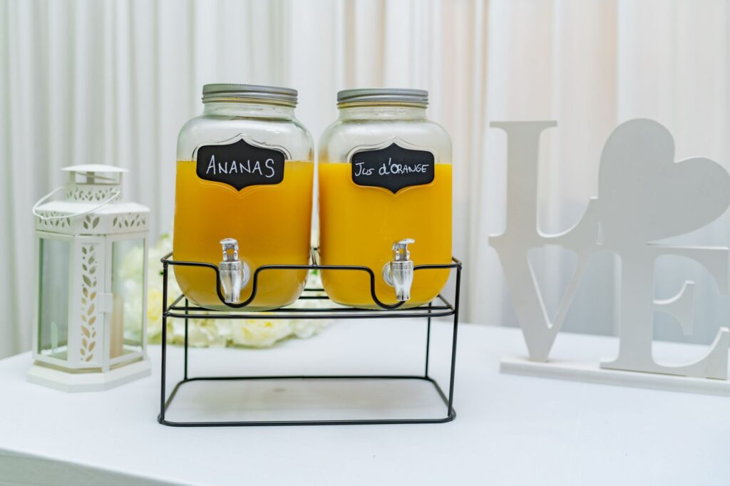 Large glass continuous brew kombucha dispenser with wooden spigot on kitchen counter filled with fermenting tea