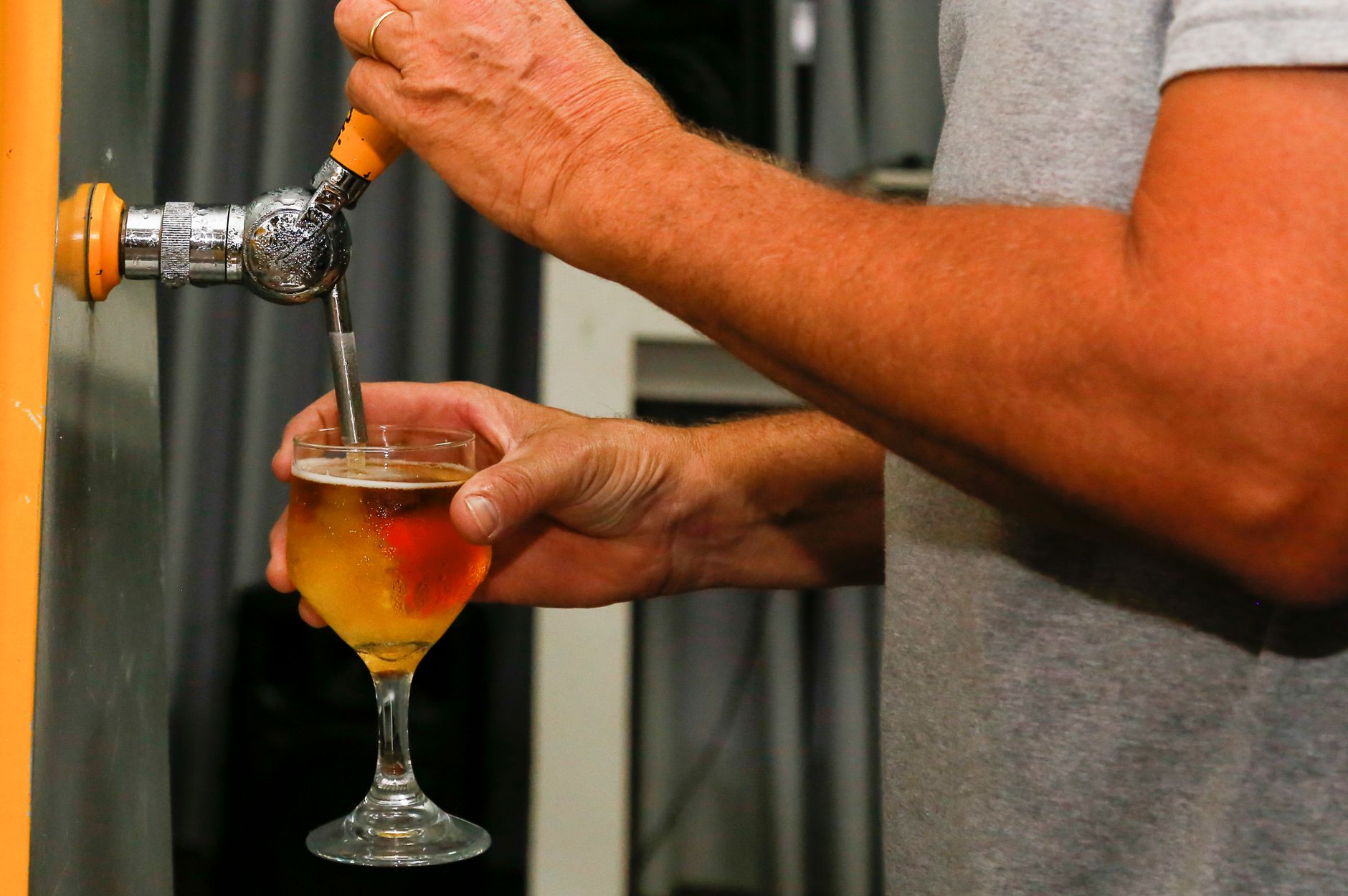 Fresh kombucha being poured from spigot tap into glass jar for bottling and flavoring