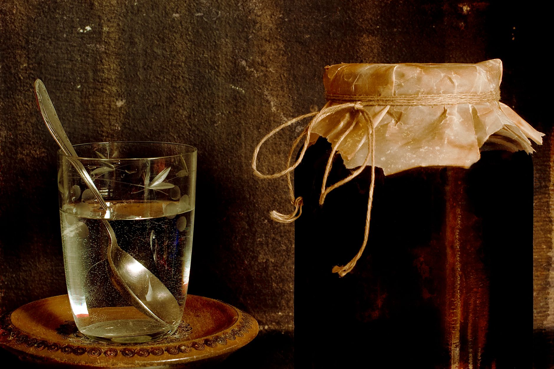 Brown yeast strings and cloudy sediment visible inside a glass kombucha brewing jar — normal fermentation activity