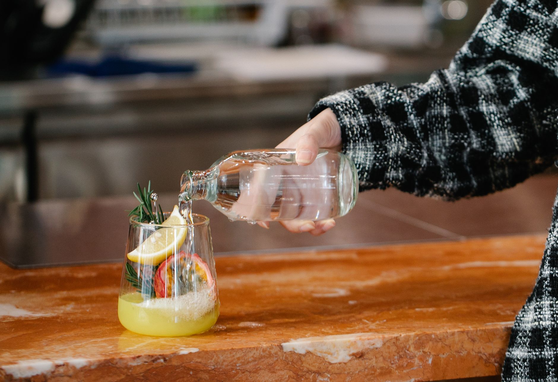 Fizzy kombucha being poured into a glass on a kitchen counter, illustrating acidity that may irritate the stomach lining.