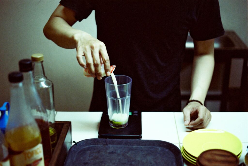 A glass of kombucha being poured on a kitchen counter in the morning, representing drinking kombucha on an empty stomach.