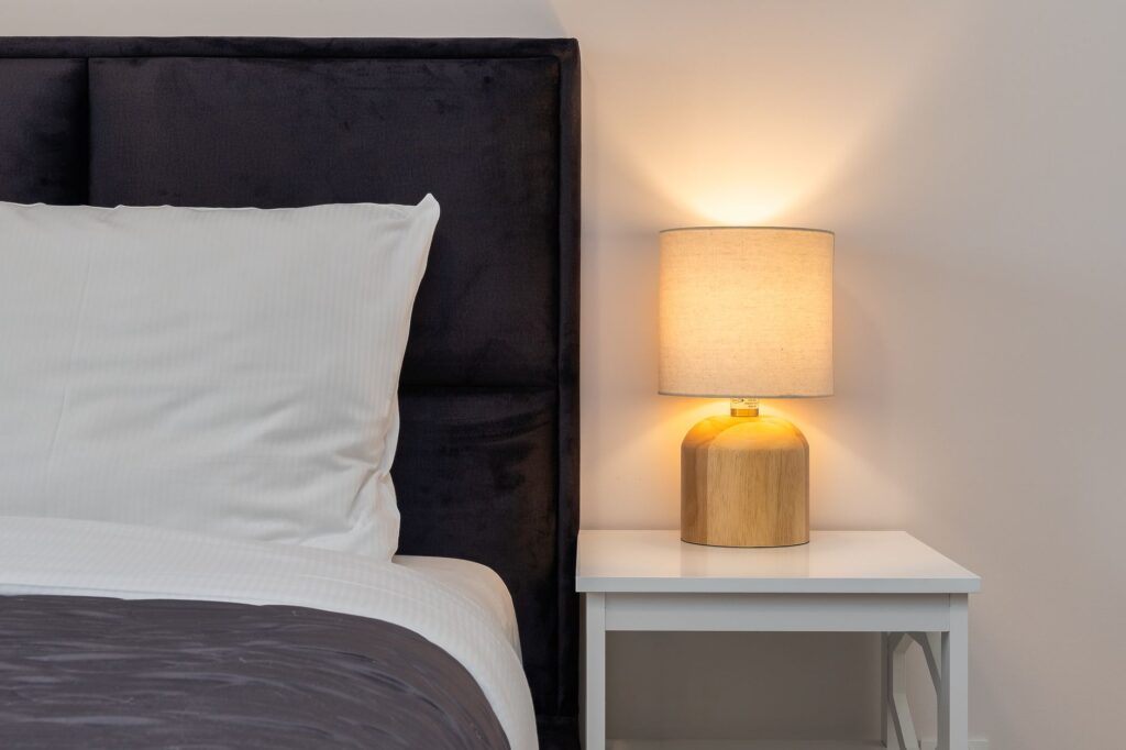 A glass jar of kombucha on a bedside table at night, soft warm lighting suggesting a relaxing evening routine.