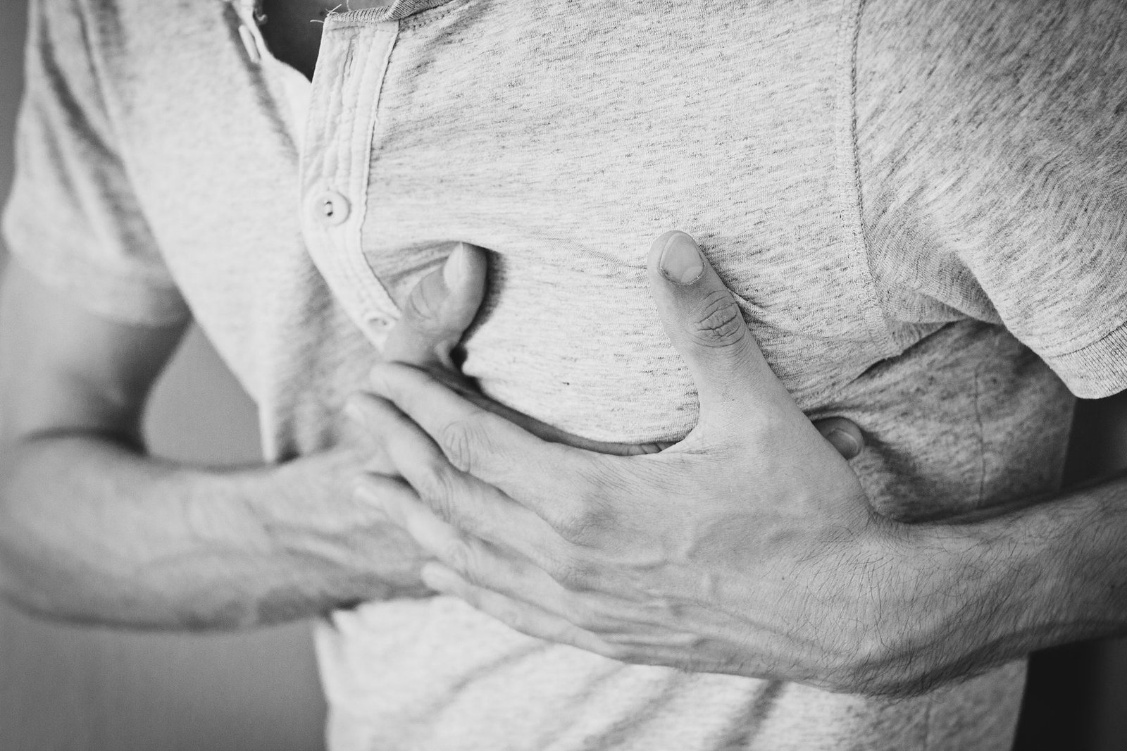 Person pressing hand to chest experiencing heartburn discomfort while standing in a kitchen