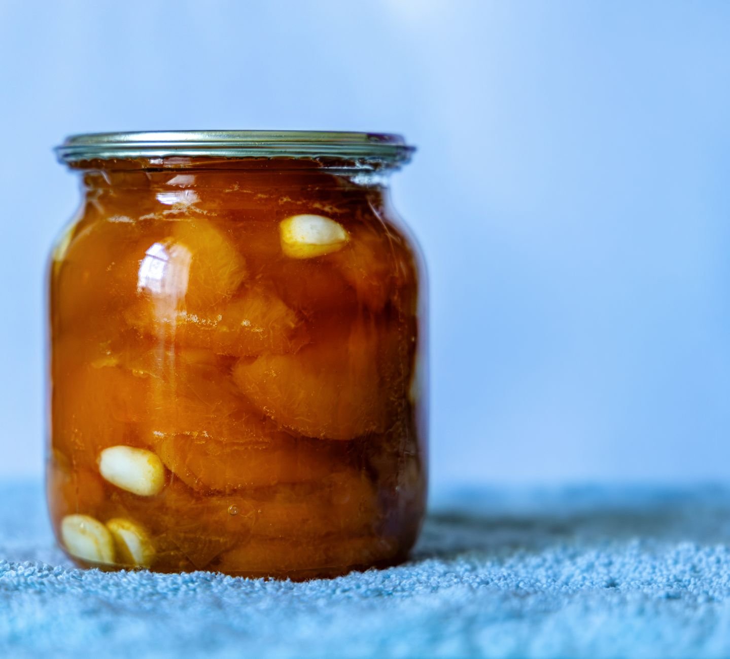 Top view of a kombucha SCOBY floating in a glass fermentation vessel with amber liquid