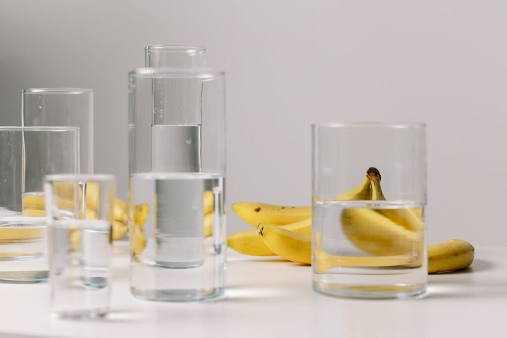 A glass of kombucha and a glass of water side by side on a kitchen counter, representing hydration and urinary health