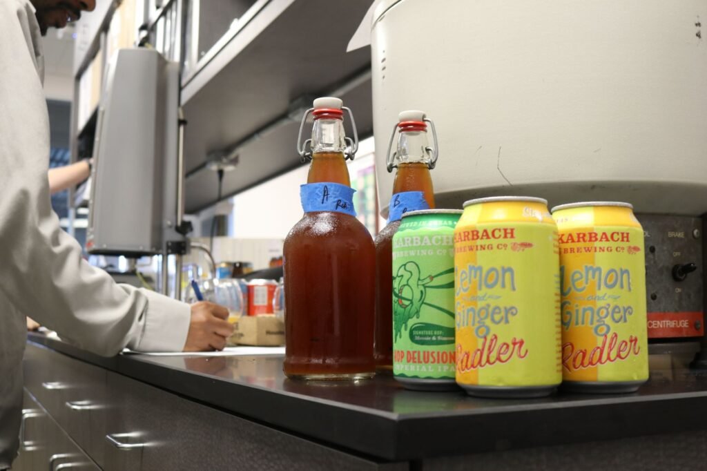 Five swing-top bottles of kombucha with unusual flavor combinations lined up on a wooden kitchen counter