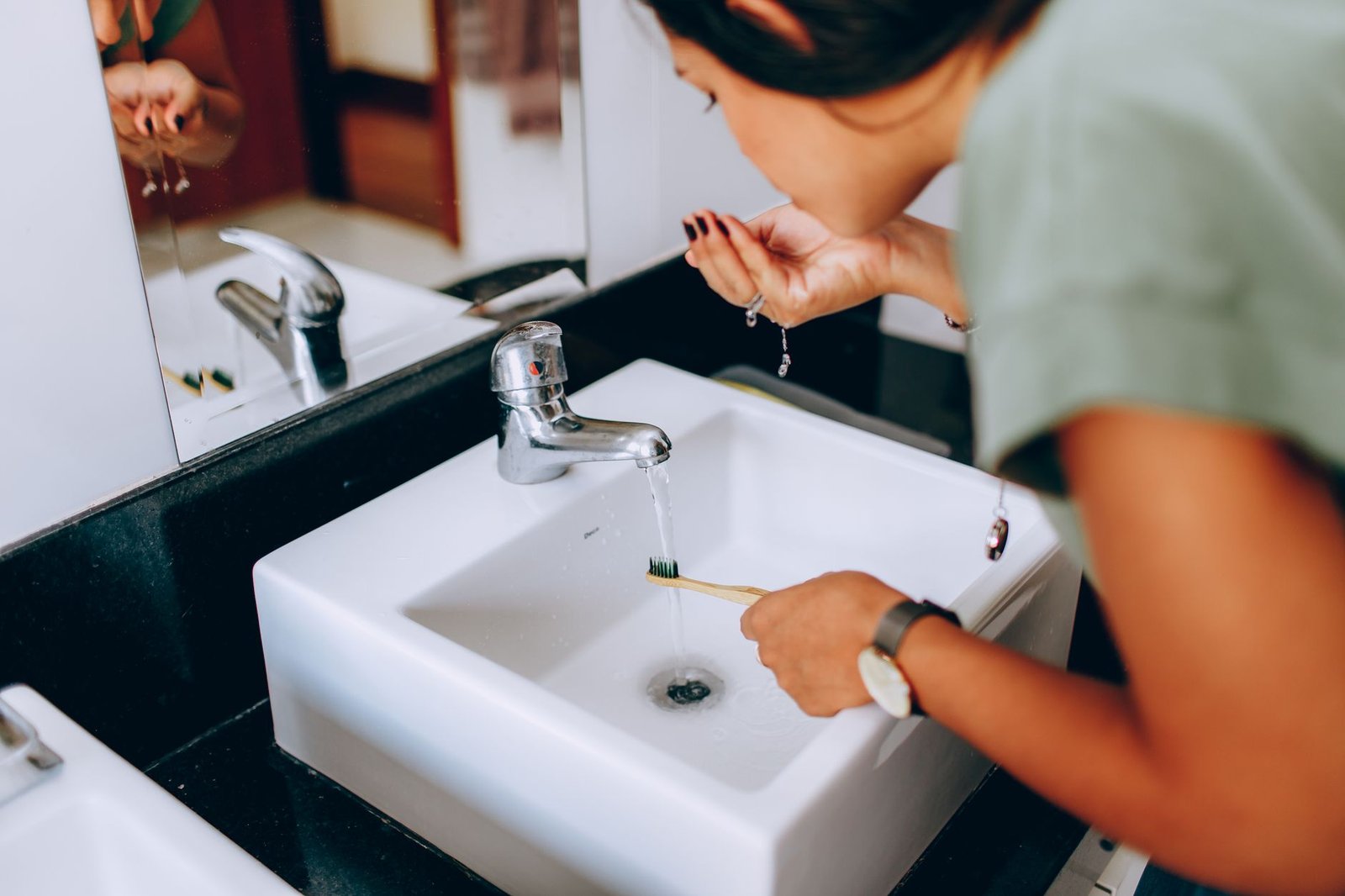 Person rinsing mouth with water after drinking an acidic beverage to protect enamel