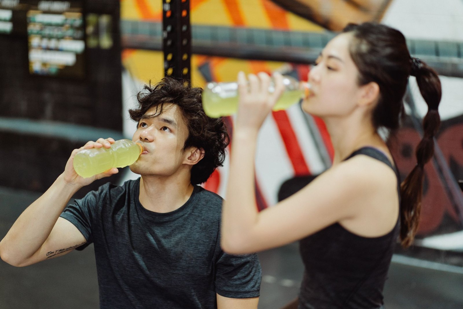 A bottle of kombucha being poured into a glass on a kitchen counter before a workout