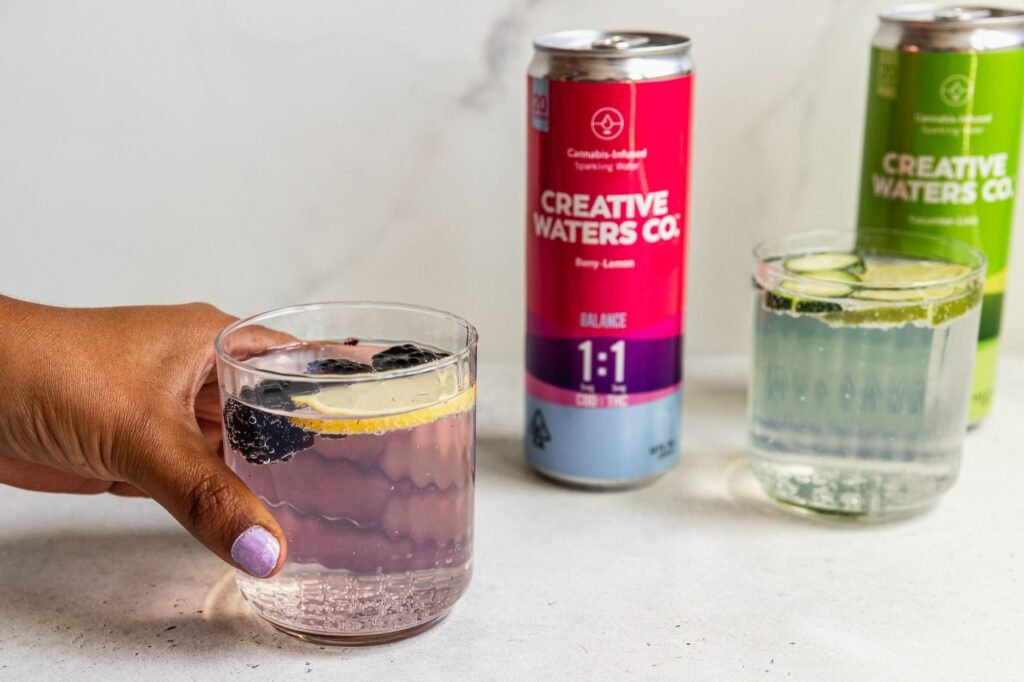 A bottle of kombucha and a can of sparkling water placed side by side on a kitchen counter for comparison