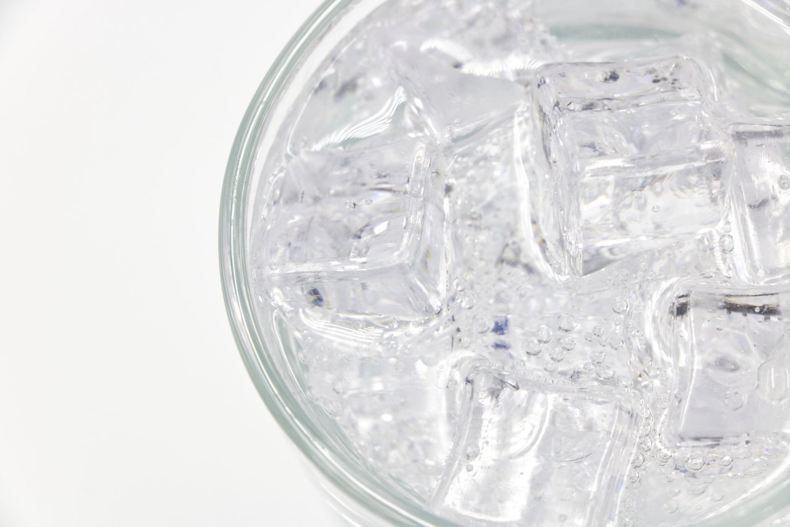 Sparkling water being poured into a clear glass from above showing rising bubbles