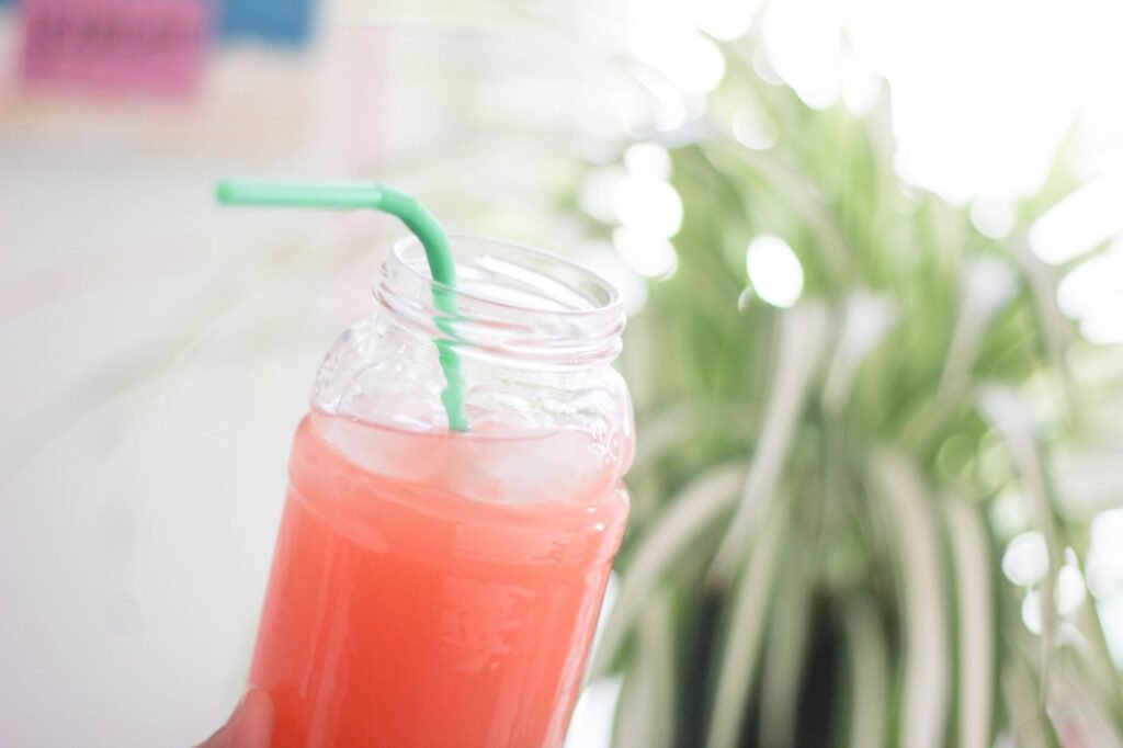 Close-up of a glass jar of kombucha on a sunlit kitchen counter, showing the golden fermented liquid inside.